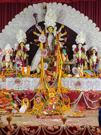 A full view of a Durga Puja pandal where devotees are offering prayers to the grand idol.
