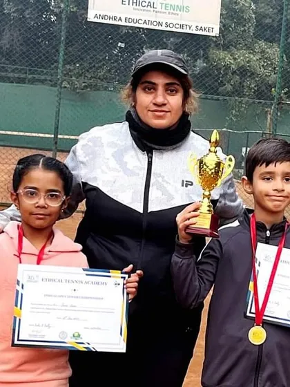 A coach stands proudly with two of our youngest champions from the Saket Ethical Open Tournament. We believe in celebrating every victory, and these big trophies for our U8 players show that the journey to greatness starts with encouragement.