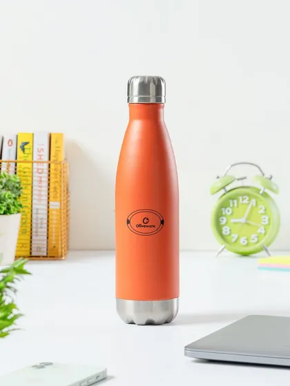 A lifestyle shot of a water bottle on a work desk. This simple, clean styling places the product in its intended environment, making it an aspirational accessory for any workspace.