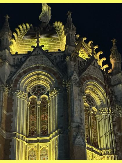 A detailed shot of the intricate carvings and stained glass windows of the CSMT building at night.
