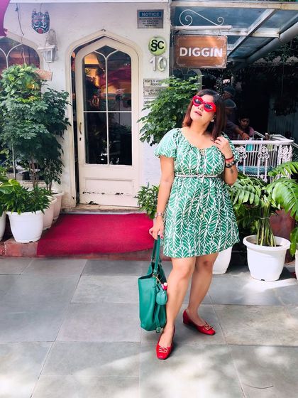 Posing outside a cafe, this outfit feels right at home. The green dress and red accessories create a striking visual that is both playful and chic, showing how to have fun with your style.