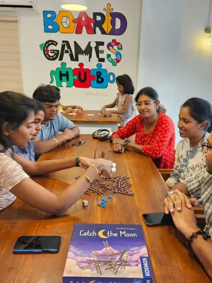 Patrons enjoying games at the Board Games Hub, with my custom-designed logo mural in the background.