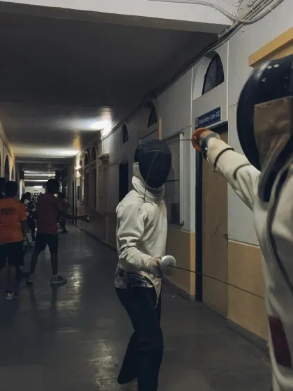 A view from behind a fencer, showing their perspective as they face an opponent down the long corridor we use for training.