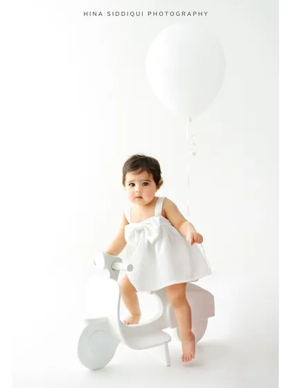 A full length view of the scooter and balloon setup. This image shows how simple props can create a complete and charming scene for a first birthday or milestone session.