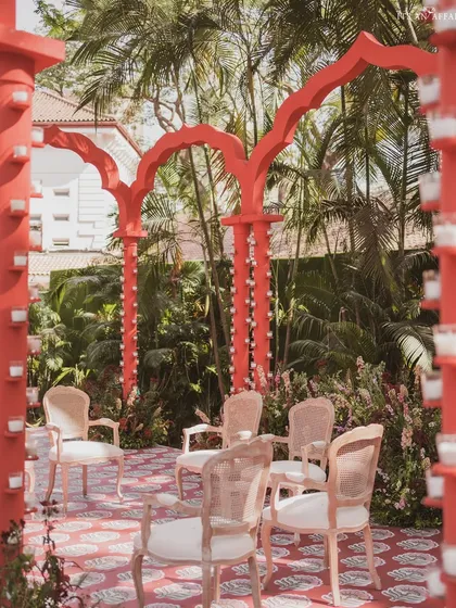 A view from within the mandap, looking out at the guest seating. The bold red arches frame the scene, creating a dramatic and immersive experience for the couple.
