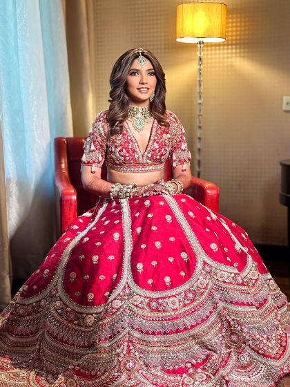Seated gracefully, Priyanka embodies the modern bride who loves tradition. Her soft makeup and flowing hair perfectly balance the grandeur of her red bridal lehenga.