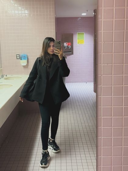 A mirror selfie showcasing a full college look: black coat, leggings, and chunky sneakers. This is a classic "outfit dump" photo that is very popular with student audiences.