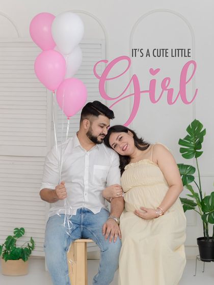 A classic and joyful gender reveal portrait with pink balloons celebrating the news that "It's a cute little Girl."