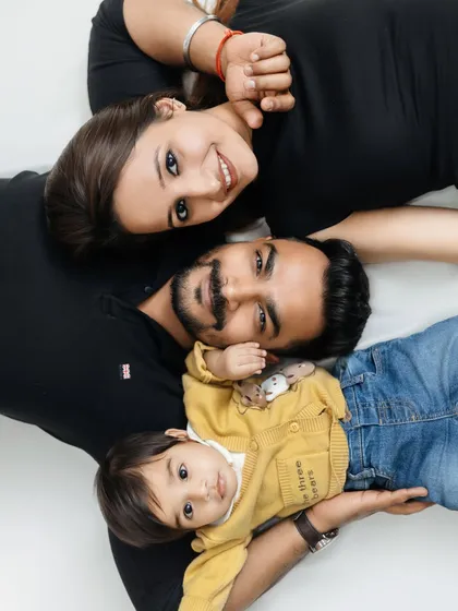 A creative and fun family portrait from a top-down perspective, showing the happy faces of mom, dad, and their little one.