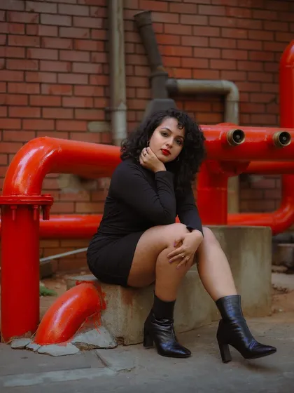 A duplicate of image 123, this full-body shot of a model in a black dress against a red brick background is a strong and visually striking image.