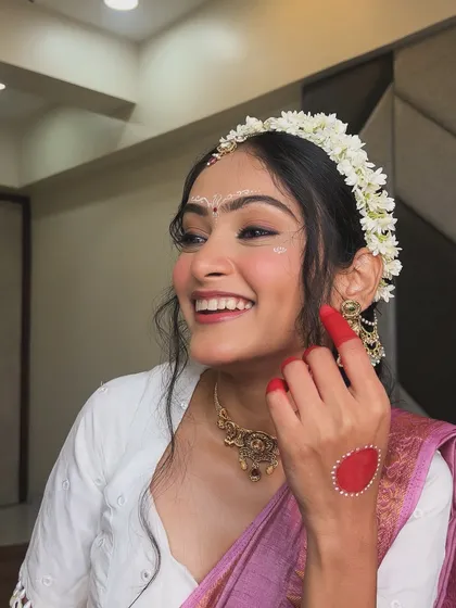 A happy, candid moment showing the intricate details of the Radha makeup, including the alta and the subtle shimmer on the face.