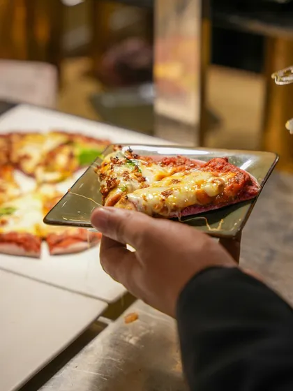 A guest selects a slice of freshly made pizza, a testament to the irresistible appeal of our live Italian cooking stations.