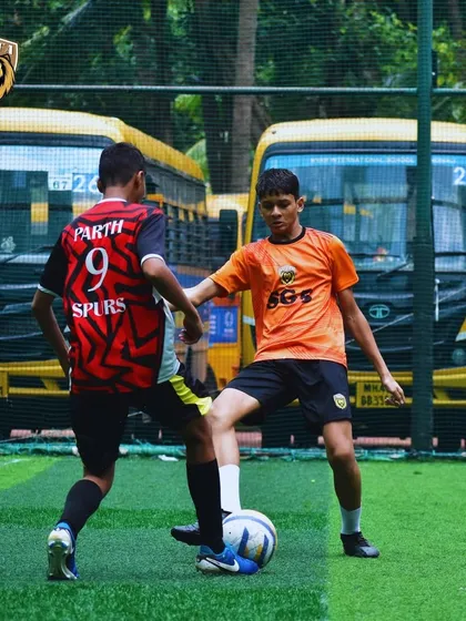 An SG5 player in orange taking on a defender from the Spurs team.