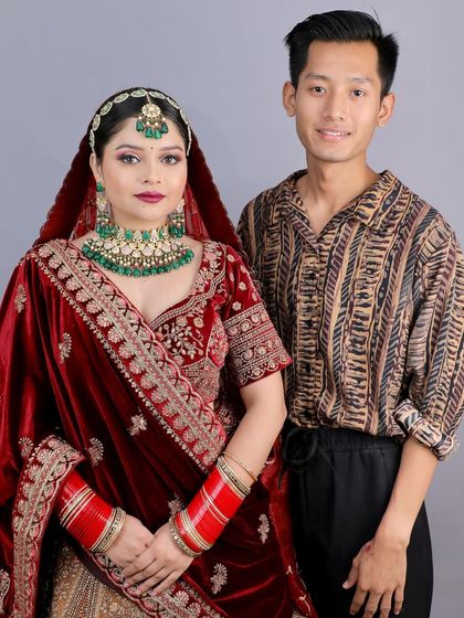 A student stands with his model, showcasing the stunning traditional bridal look he created. This is the result of dedication and expert training.