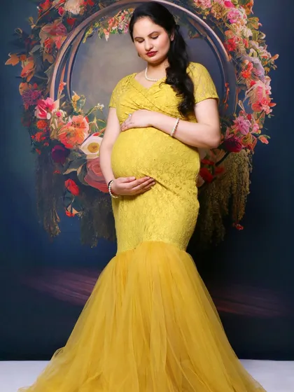 A solo portrait of the same mom-to-be, this time in a bright yellow mermaid-style gown against a floral backdrop.