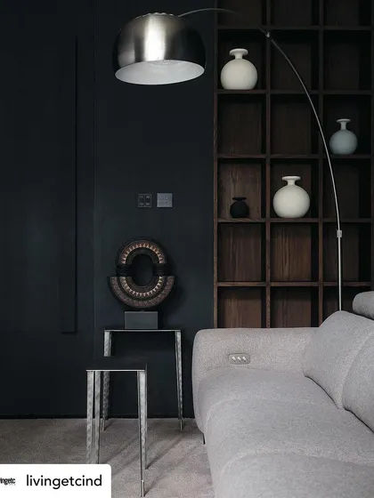 The moody and sophisticated family room, with its dark walls and curated shelving. This space, featured in Livingetc, is designed for ultimate comfort and relaxation.