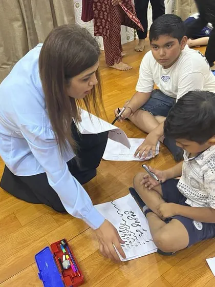 I believe in hands-on guidance. Here, I am showing two students the correct way to form calligraphy strokes on the floor.