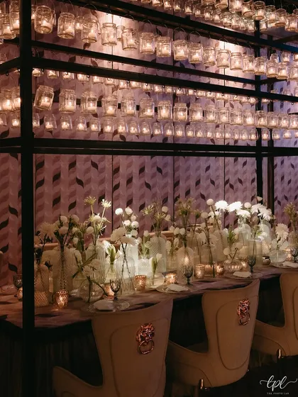 A unique dining setup with a ceiling of hanging candle-lit jars. This creative lighting solution provided a warm, intimate glow for the Sangeet dinner.