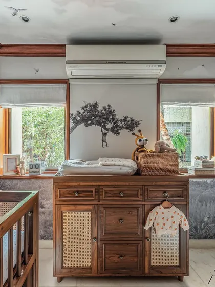 This is a different nursery project with a more serene, monochromatic theme. The focus here is on the beautiful wooden changing table with cane details, set against a subtle safari-themed wallpaper.