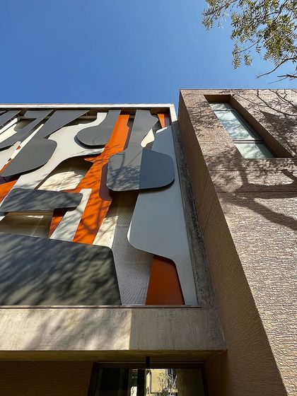 The facade of the 'Framed Austerity' house is an artwork in itself, exploring the convergence of brutalism and expressionism. The organic, flowy shapes are layered to create a dynamic and abstract composition.