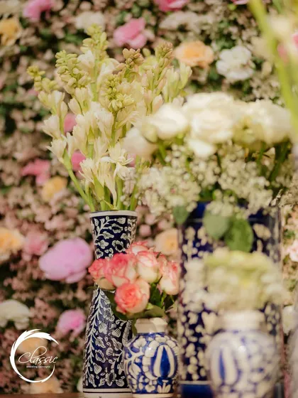 A detail shot showing delicate white and pink flowers arranged in beautiful blue and white patterned vases, adding a touch of classic elegance to the Mehendi decor.