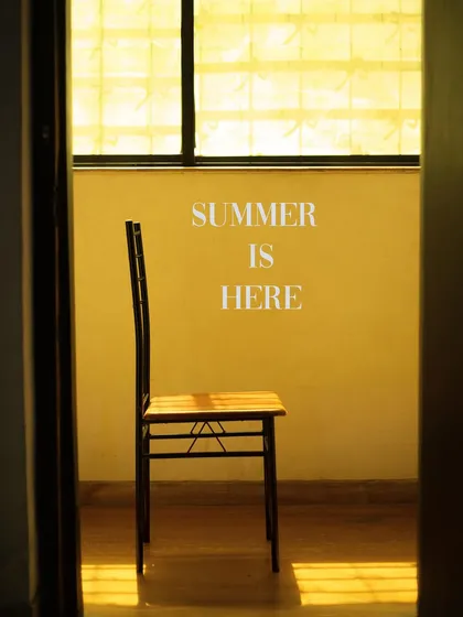 An atmospheric shot of an empty chair in the sun. This image evokes a feeling of peace, warmth, and the quiet start of summer.