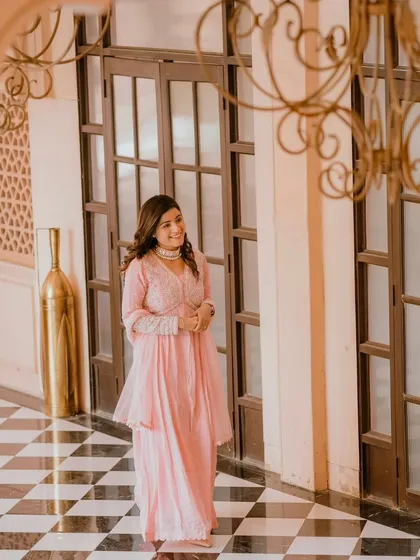 A beautiful shot in a grand corridor. The makeup is elegant and timeless, complementing the classic architecture and her soft pink attire.