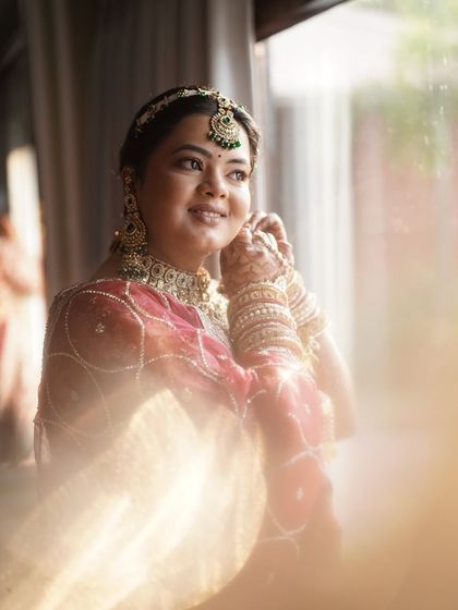 The final touches. This candid shot captures the soft, glowing makeup we created, highlighting her features beautifully in the natural light. The look is completed with elegant green-accented jewelry.