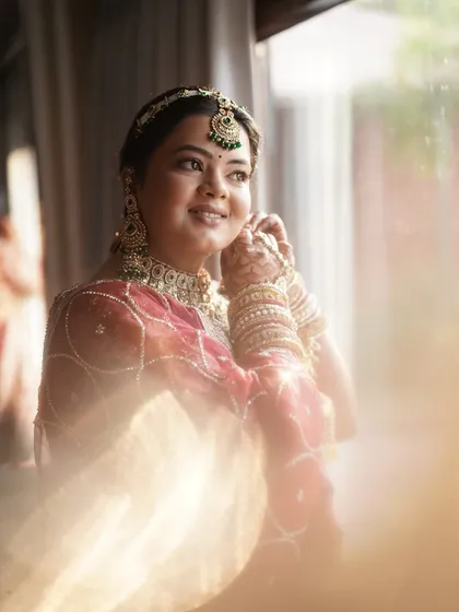 The final touches. This candid shot captures the soft, glowing makeup we created, highlighting her features beautifully in the natural light. The look is completed with elegant green-accented jewelry.