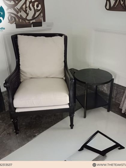 A classic high-back armchair with caned sides and a dark wood finish. Paired with a simple side table, it creates a perfect reading corner.