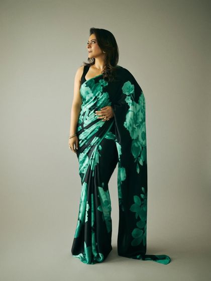 A full-length view showing the dramatic flow and pattern of the black and green saree.