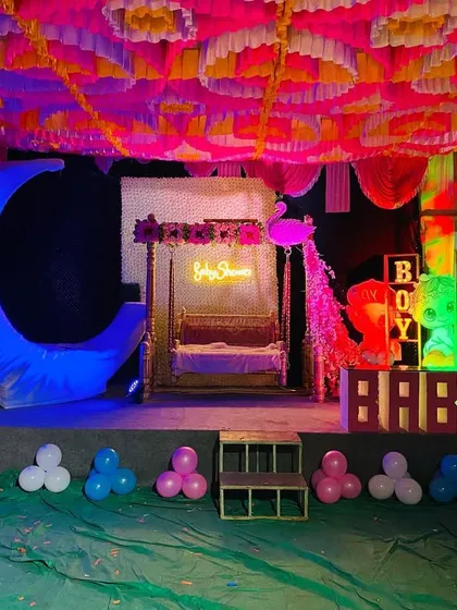 Another view of the baby shower stage under blue lighting, highlighting the moon prop and neon sign.
