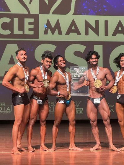 The lineup of champions at Muscle Mania India. My client is right there in the middle, holding the plaque, a testament to his hard work and my coaching.