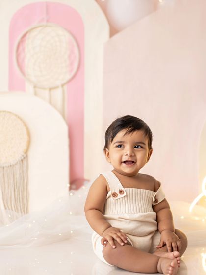 A happy little guy in his cute overalls, enjoying his first birthday photoshoot.