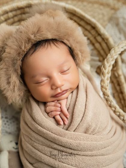 This baby looks so cozy wrapped in neutral beige tones and wearing an adorable bear bonnet. The natural jute rug adds a lovely rustic texture to the setup.