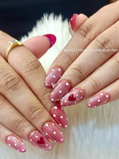 A close-up of the sweet and subtle Valentine's polka dot and heart nails, showing the beautiful almond shape and glossy finish.