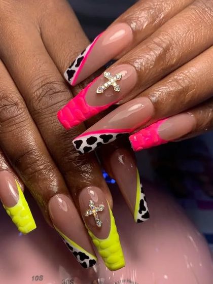 This bold look combines neon yellow and pink tips, cow print, a textured finish, and large crystal cross charms.