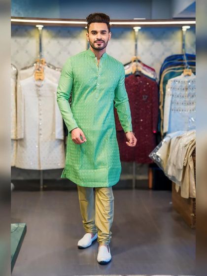 A full-length view of Ayush Khatri in the green kurta, paired with beige trousers. This shows how to style a bright kurta for a balanced and elegant look.