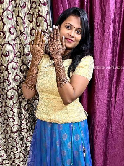 The happy client showing off her elegant engagement mehendi.
