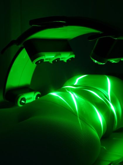 A close-up, dramatic shot of the Emerald Laser targeting the back of the thighs and buttocks. The green light penetrates the skin to reach stubborn fat deposits, helping to smooth and contour the area without any pain or surgery.