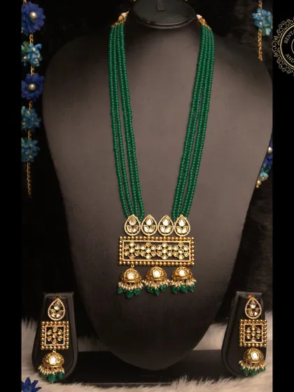 Rent our green beaded Kundan necklace set for an everlasting impression. The rectangular pendant and matching jhumkas create a unique and modern silhouette.