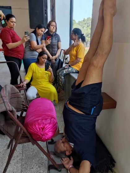 A supported headstand with students observing.