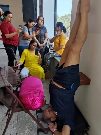 A supported headstand with students observing.