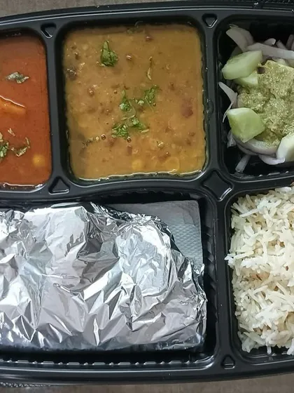 A standard daily thali with a mixed vegetable curry, a light lentil soup, fluffy rice, and soft rotis. This is the ideal balanced meal for your daily needs.