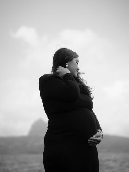 A classic black and white silhouette of the mom-to-be against a cloudy sky, her hand gently resting on her bump.