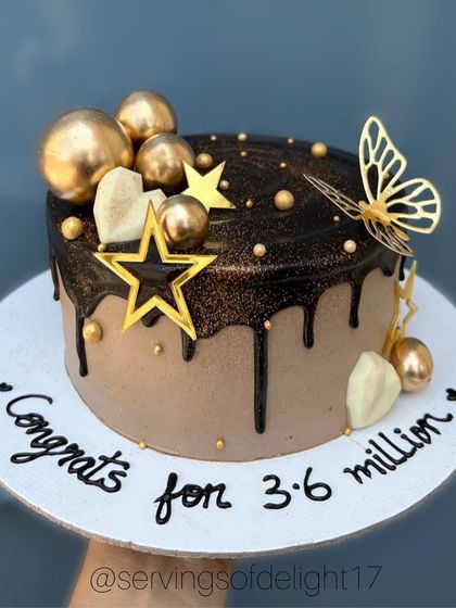 A rich chocolate drip cake decorated with gold stars, spheres, and a butterfly. This cake was made to celebrate a huge milestone.