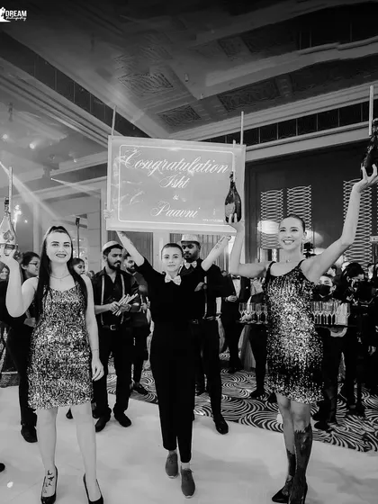 The grand entrance at Isht and Paavni's Sagan, with performers holding champagne and a congratulatory sign.