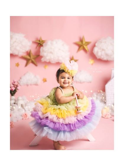 A sweet little girl in a rainbow tutu, celebrating her first birthday with a stars and clouds theme.