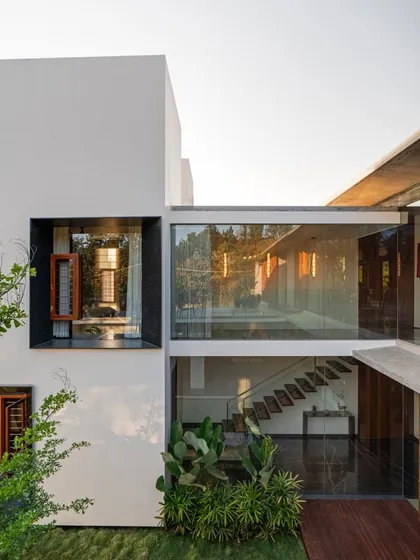 A view into the central courtyard, showcasing the glass bridge that connects two sections of the upper floor. This transparent element maintains visual openness and allows light to penetrate deep into the home's core.