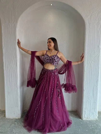 A happy and confident pose in this stunning wine-colored lehenga. It's a perfect outfit for dancing the night away at a sangeet.